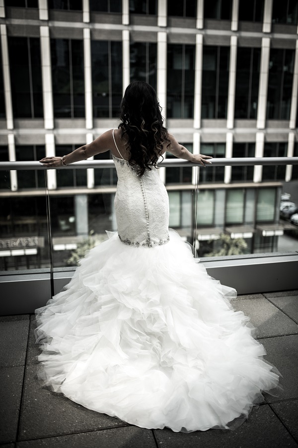Photo of a woman in her wedding dress standing on a balcony