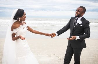 Photo of African American Bride and Groom Standing by the Beach