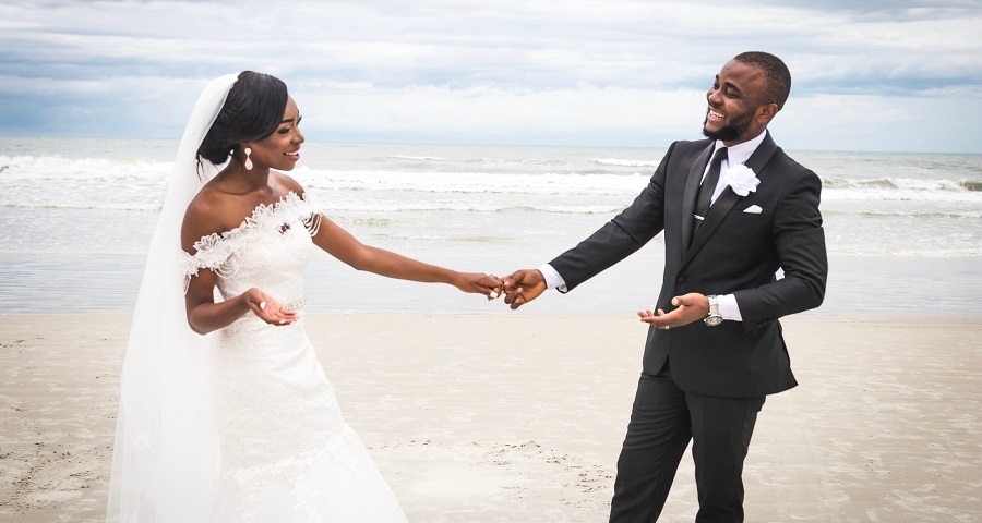 Photo of African American Bride and Groom Standing by the Beach