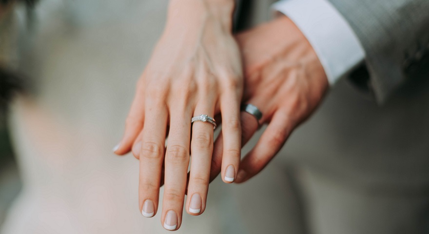 Photo of bride and groom showing off their wedding ring