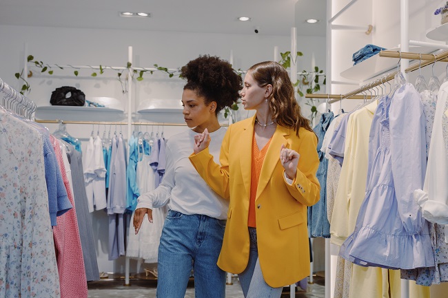 Photo of fashion women searching for clothes to buy in a shop