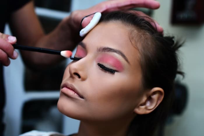 Photo of makeup artist applying makeup on a client