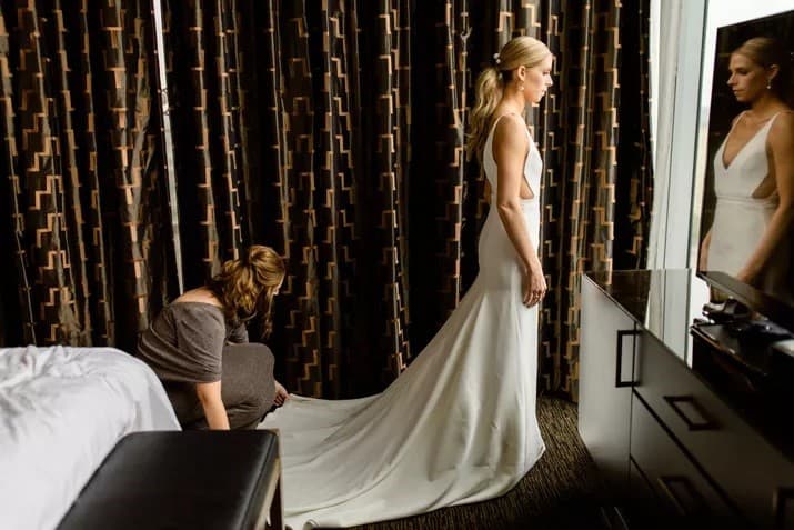 Mother of the bride arranging bride's wedding dress photo