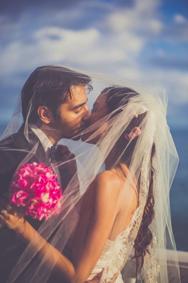 Photo of briade and groom kissing under veil