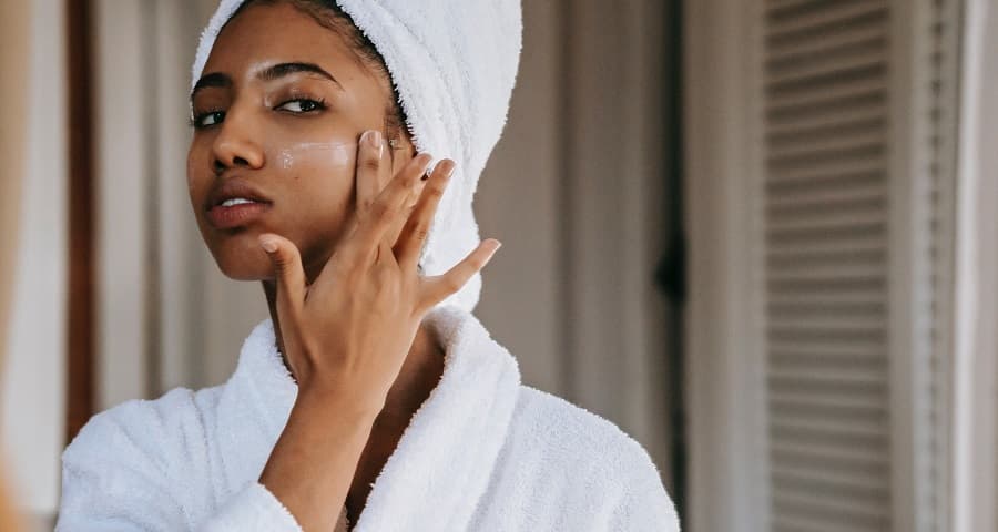 African American woman moisturizing her skin