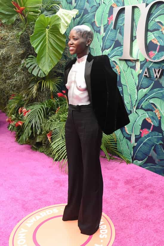 Lupita Nyongo attends the 2023 Tony Awards wearing silver breastplate and black velvet suit