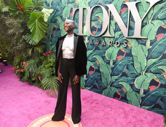 Lupita Nyongo attends the 2023 Tony Awards wearing silver breastplate and black velvet suit