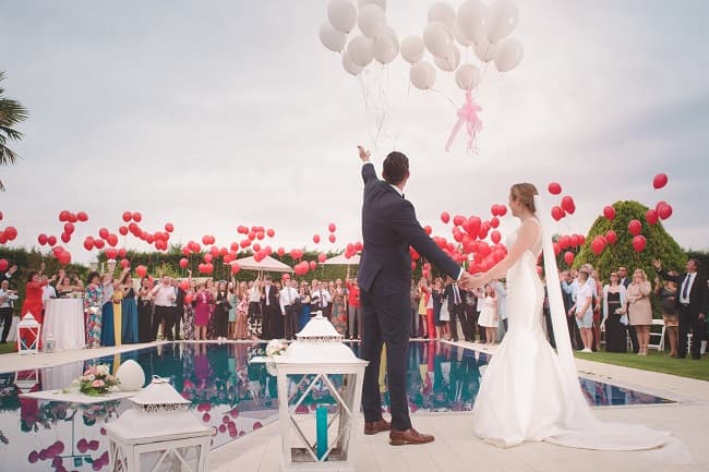 photo of the groom and bride standing in front of balloons - Fashion Police Nigeria