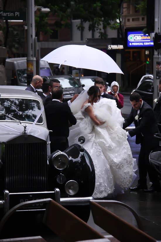 Groom covering bride with umbrella during rainfall photo - Fashion Police Nigeria