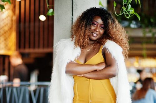 Glamour African-American woman yellow-dress white woolen cape posed restaurant near column - Fashion Police Nigeria