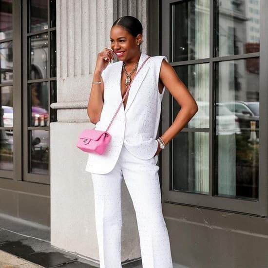 African American woman wearing an all white outfit with a tiny pink chain bag
