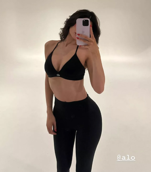 Kylie Jenner in Sports Bra and Leggings holding phone and facing mirror Fashion Police Nigeria