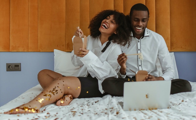 photo of black couple watching a movie on the bed with a laptop-Fashion Police Nigeria