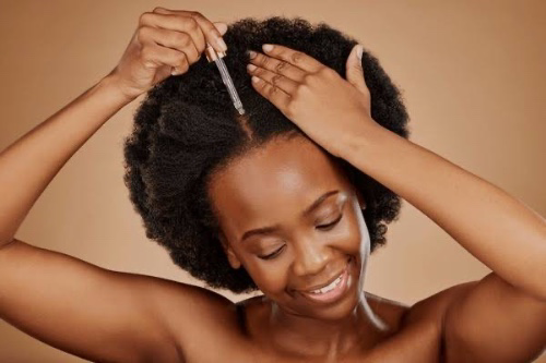 Photo of black woman rubbing oil on hair