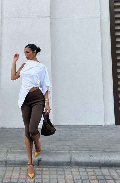 A stylish woman dressed up in a white shirt and brown capri pants outfit 