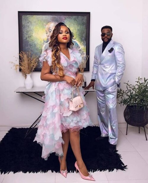 A photo of a Nigerian wedding guest couple attending a wedding in a beautiful dress for the woman while the man wore a suit.