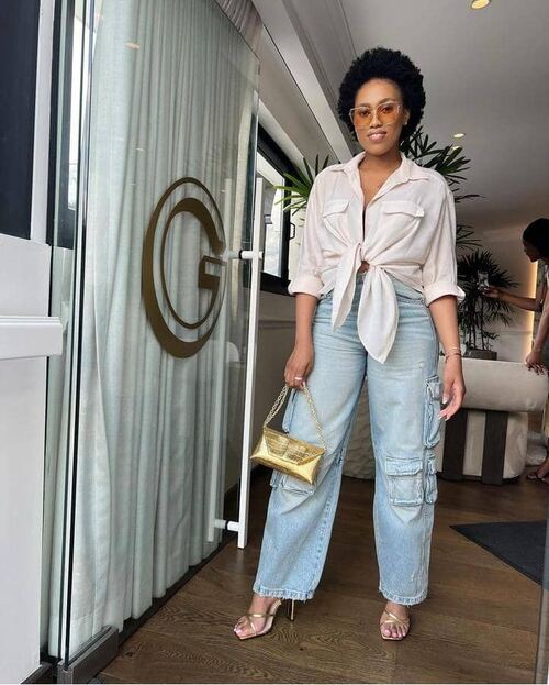 African American Afro haired woman wearing a button-down shirt with two pockets, wash denim pants and heel sandals