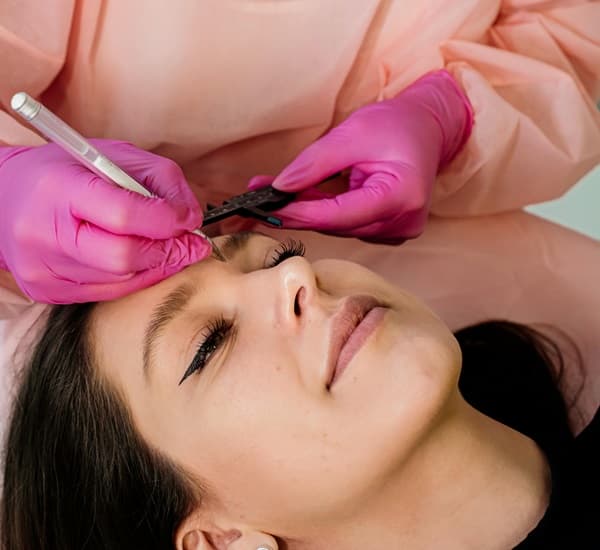 Woman receives the eyebrow microblading procedure with a technician - Fashion Police Nigeria