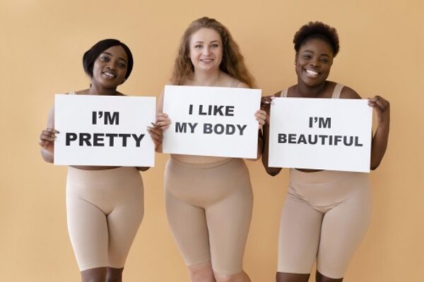 Three women holding placards with body positivity statement - Fashion Police Nigeria