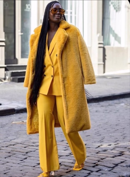 Chic photo of African American woman wearing a mustard fur coat over matching mustard pantsuit - Fashion Police Nigeria
