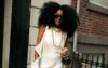 Photo of a beautiful black woman wearing a satin sleeveless dress and her hair in afro walking the street