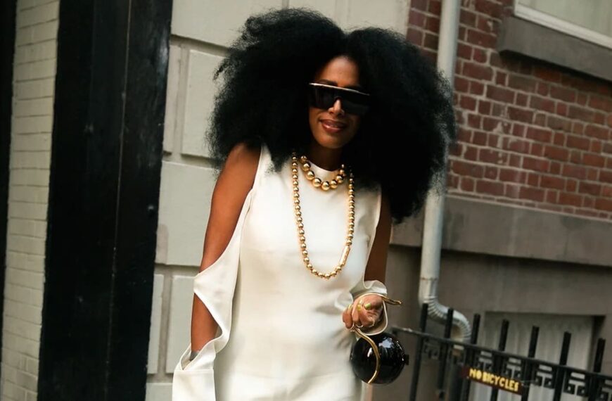 Photo of a beautiful black woman wearing a satin sleeveless dress and her hair in afro walking the street