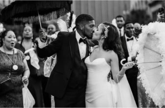 Black and white photo of bride and groom kissing in front of the wedding guests - Fashion Police Nigeria