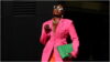 photo of a lady on a pink blazer, orange pants and carrying a green bag