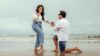 A man proposes to a woman on a scenic beach, capturing a lifelong memory.
