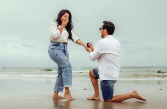 A man proposes to a woman on a scenic beach, capturing a lifelong memory.