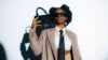 A woman in a coat and tie holding a purse