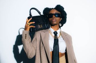 A woman in a coat and tie holding a purse